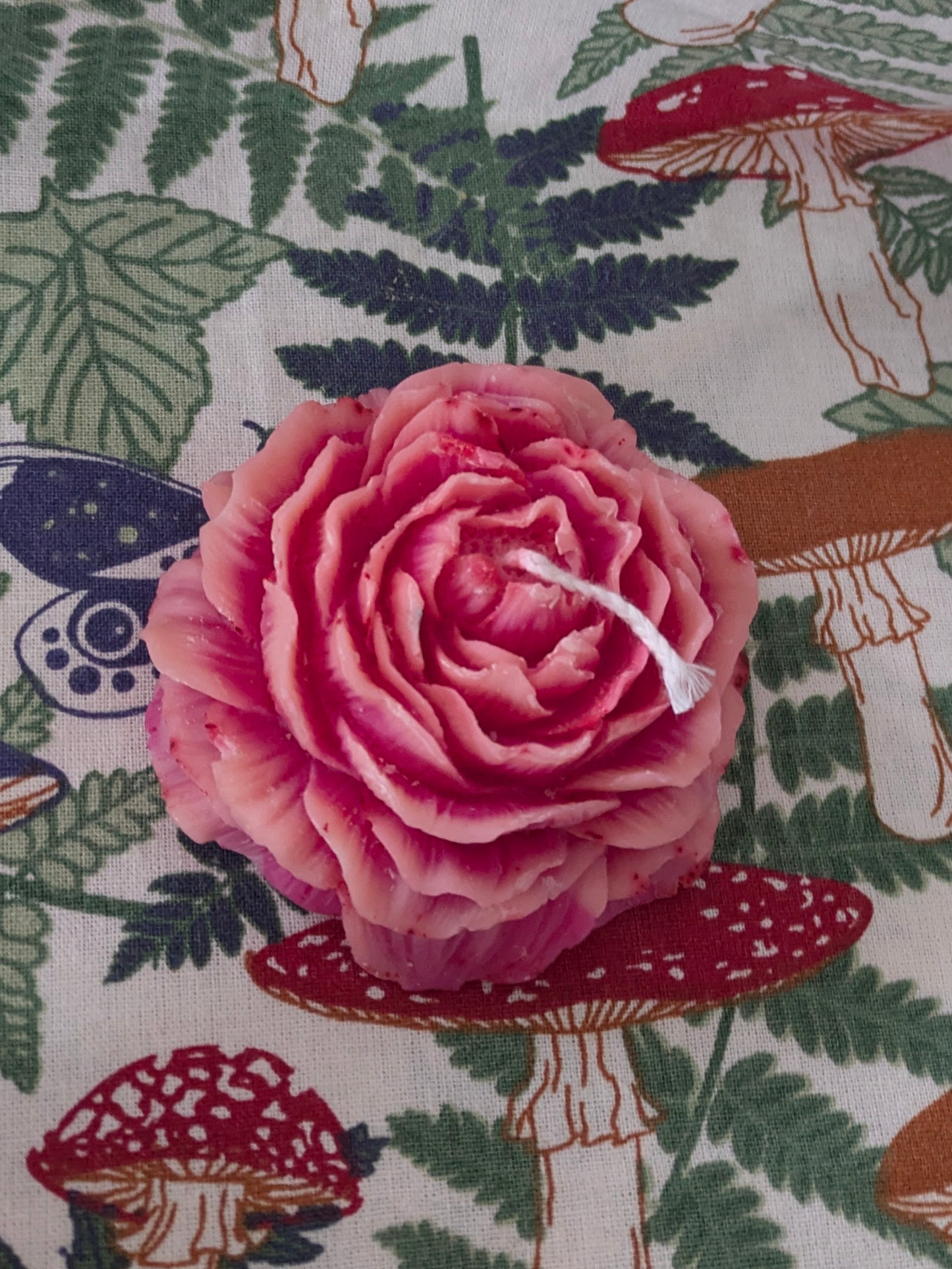 Pink Peony Rose candle by VitaUnlimited with a lit wick, featuring a soft pink floral design and a warm, inviting glow.