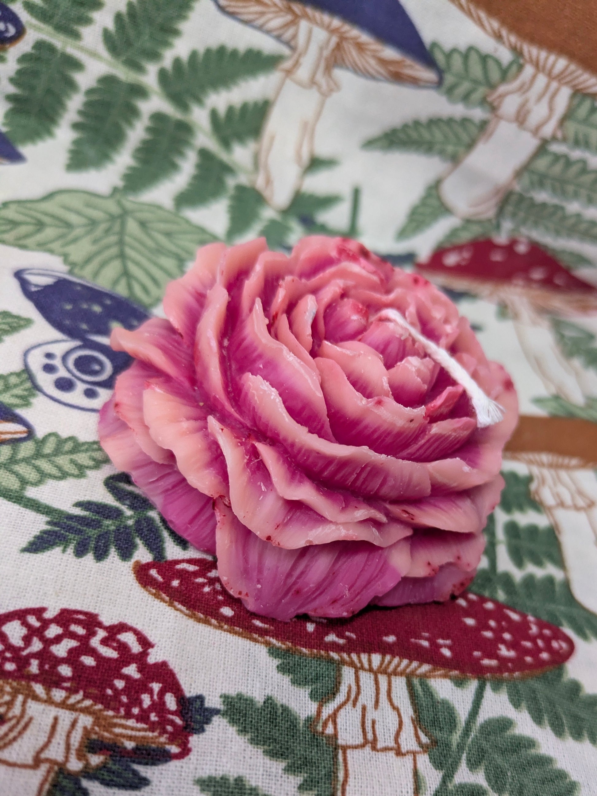 Pink Peony Rose Candle by VitaUnlimited featuring a pink floral design and a lit wick, perfect for creating a cozy ambiance.